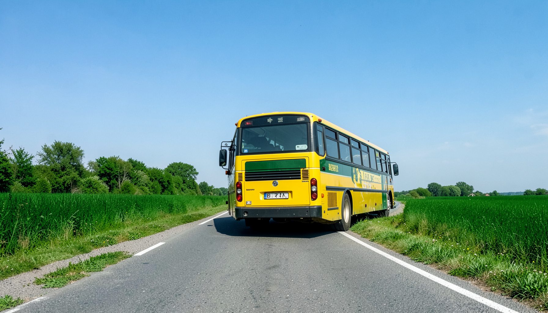 Bus scolaire à moteur arrière profilé sur une route de campagne sous un ciel bleu.
