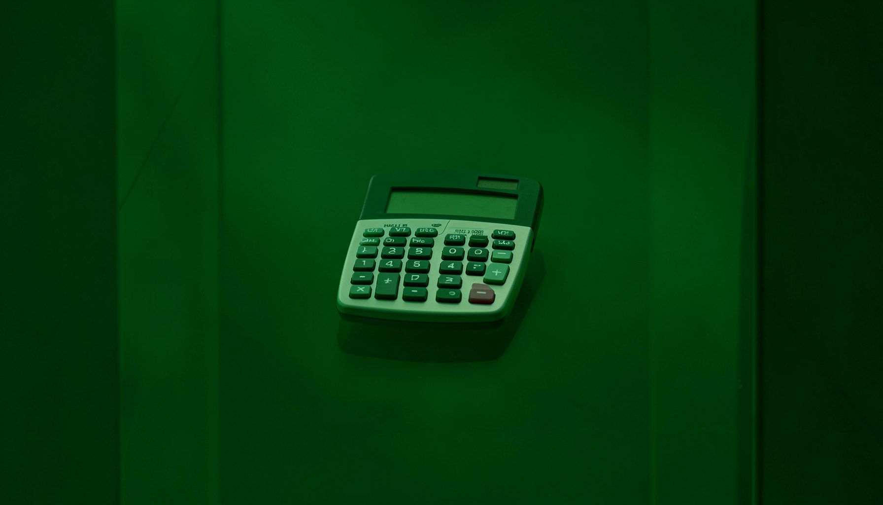 Contrat et calculatrice sur une surface de verre, avec un éclairage vert discret, évoquant la planification financière et la flexibilité budgétaire.