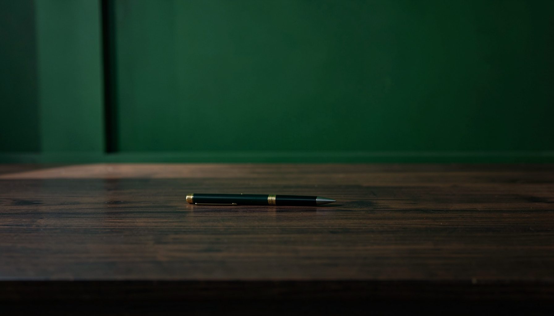 Document officiel et stylo posés sur un bureau en bois sombre, éclairés par une lumière douce, symbolisant la protection et la conformité.